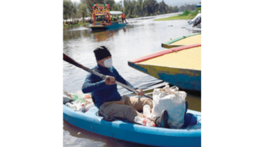 Mexicano recoge, con sus manos, la basura en canales de Xochimilco